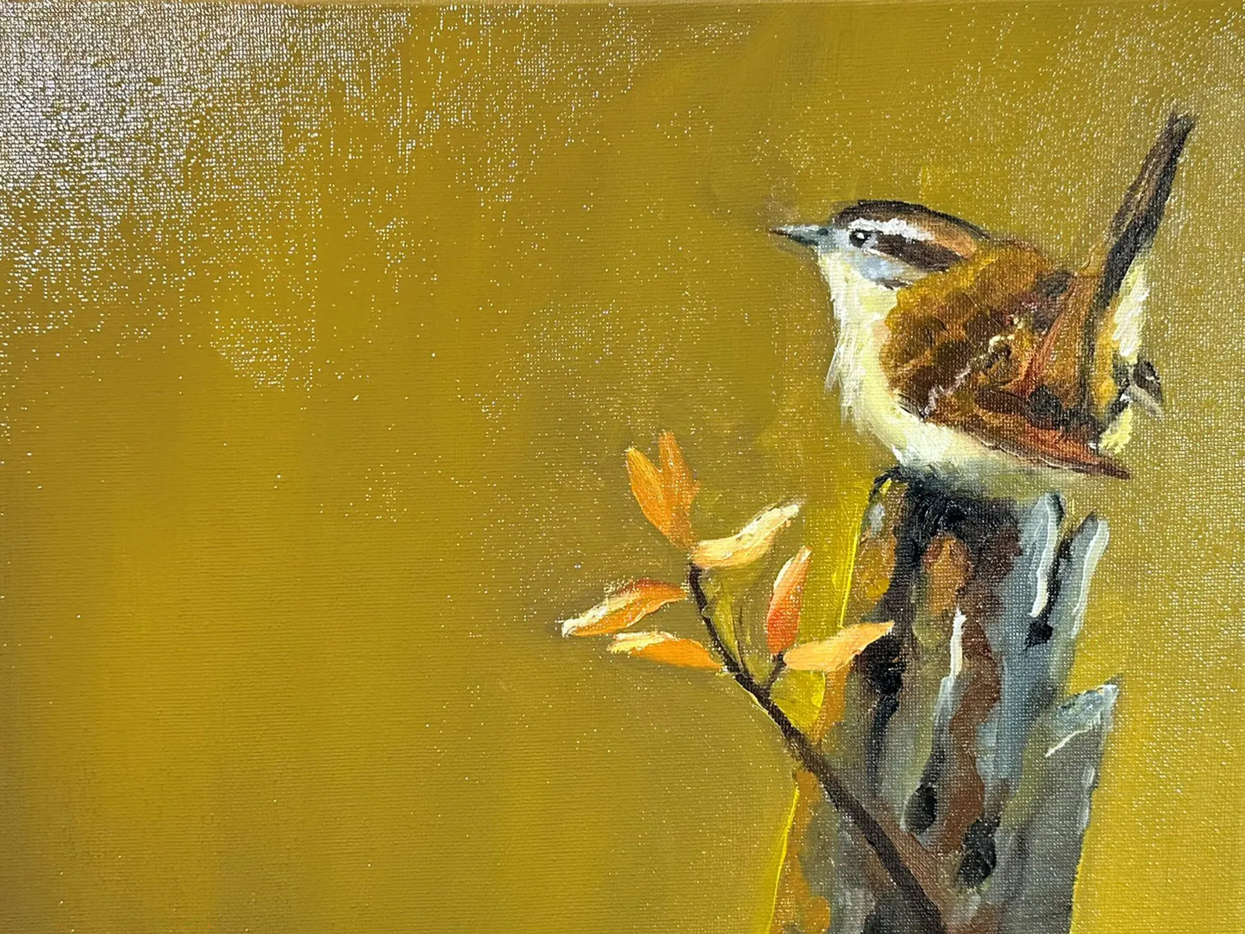 A small bird positioned on the right side of a quiet yellowish brown field, with open space extending to the right.